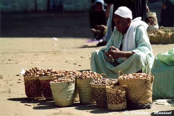 old merchant sitting near full baskets