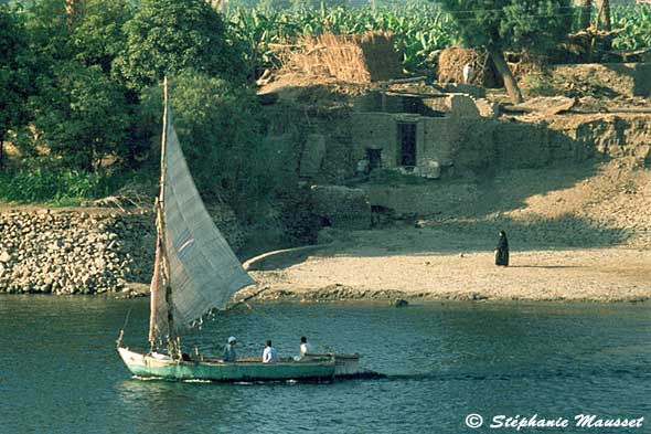 une felouque passe près d'un village sur les berges du Nil