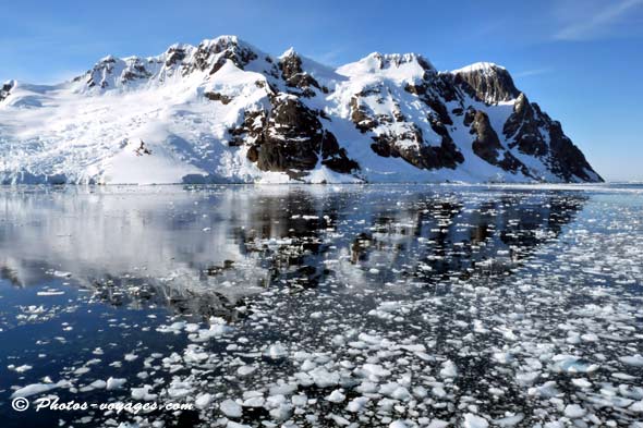 reflet d'un sommet enneigé dans un océan de glaçons en Antarctique