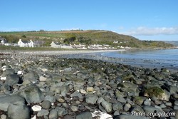 Plage de galets et côte rocheuse bordée de maisons et de collines en Irlande du Nord