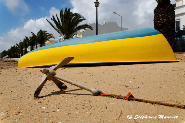 bateau retourné sur une plage et ancre dans le sable