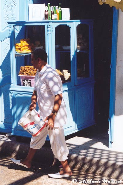 Tunisian trader waters the street with a bucket